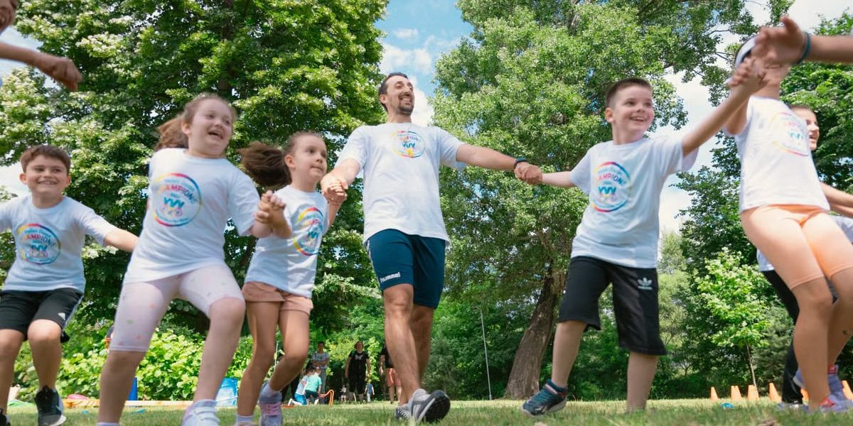 Group of joyful children playing outdoors with an instructor in a sunny park.
