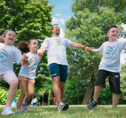 Group of joyful children playing outdoors with an instructor in a sunny park.