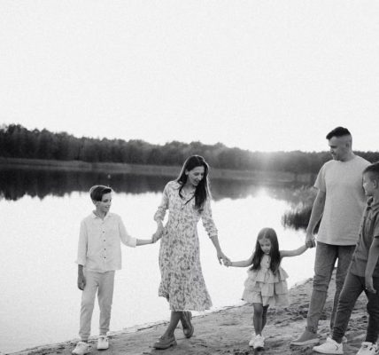 Monochrome photo of a family walking hand in hand along a serene lakeshore.