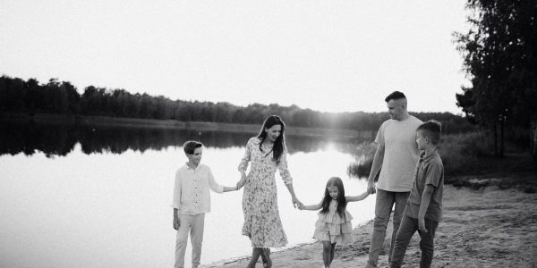Monochrome photo of a family walking hand in hand along a serene lakeshore.
