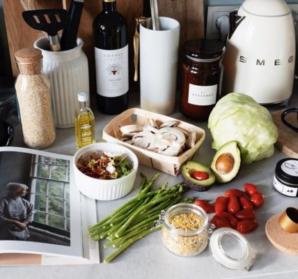 Various colorful healthy food and vegetables locating on countertop next to many different utensils and white kettle during cooking in stylish kitchen